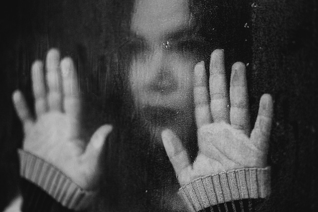woman looking stressed with hands on a window